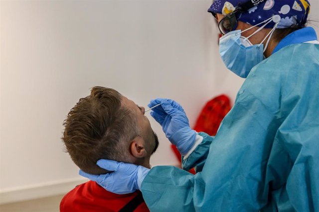 Archivo - Un sanitario toma muestras a un hombre a través de un frotis de nariz para realizar un test de antígenos.