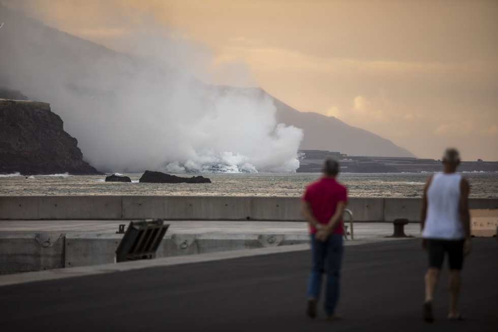Dos personas observan la columna de humo y la lava del volcán de Cumbre Vieja a su llegada al Océano Atlántico, a 29 de septiembre