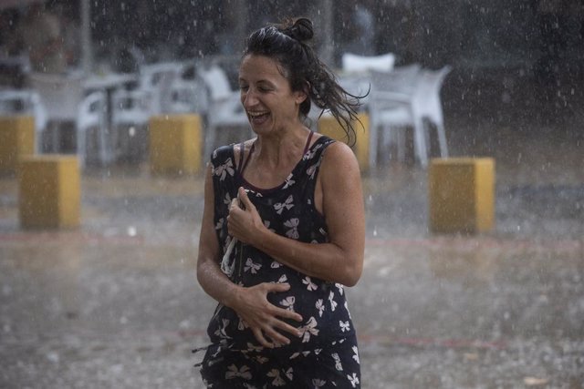 Una mujer corre bajo la lluvia. A 14 de septiembre de 2021, en Sevilla (Andalucía, España).