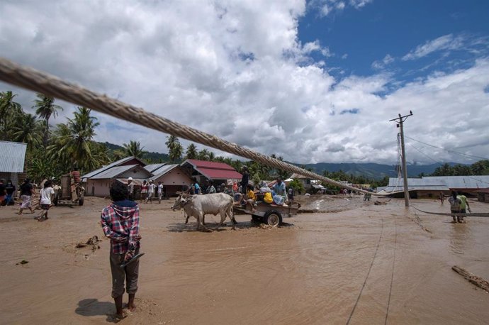 Archivo - Los residentes transitan a través de un camino fangoso después de inundaciones en la isla de Sumatra.