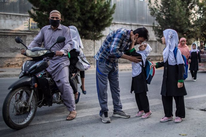 22 September 2021, Afghanistan, Kabul: A young Afghan girl gives her father a kiss before attending a primary school in Kabul, Afghanistan. The new Taliban government has banned girls from secondary school education in Afghanistan, by ordering high scho