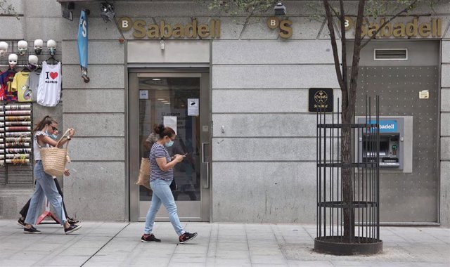 Dos mujeres pasan por una sucursal de banco Sabadell,  a 2 de septiembre de 2021, en Madrid (España).