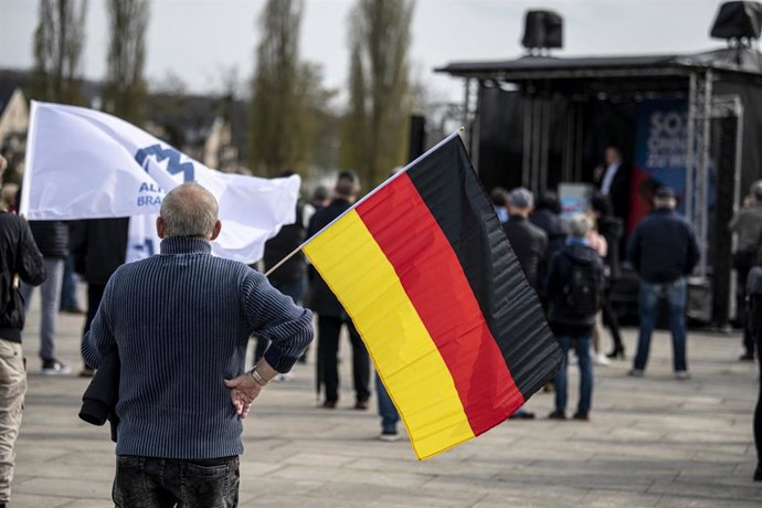 Archivo - Un hombre sostiene una bandera de Alemania en Postdam. 