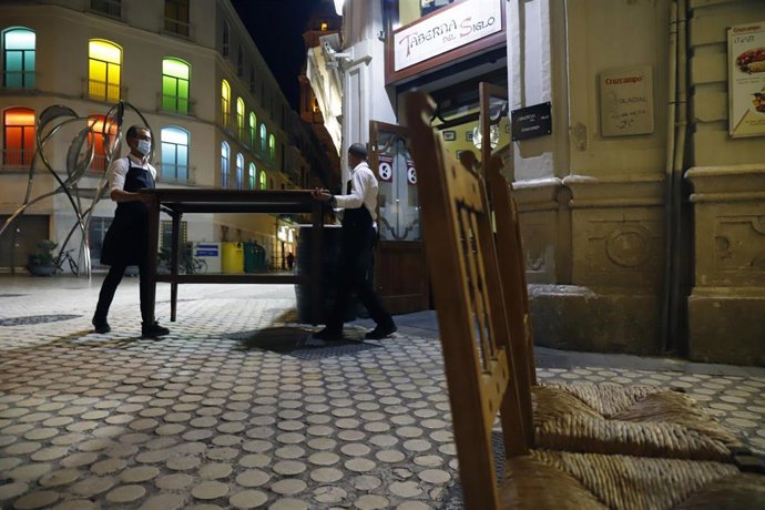 Archivo - Imagen de archivo de dos camareros recogiendo la terraza de un bar ubicado en el centro de Málaga capital