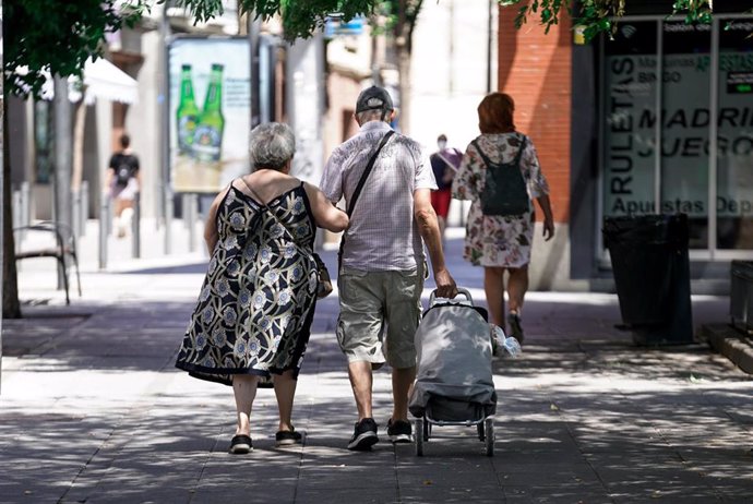 Archivo - Una pareja de personas mayores camina por la calle con un carro de compraen Madrid, (España). 
