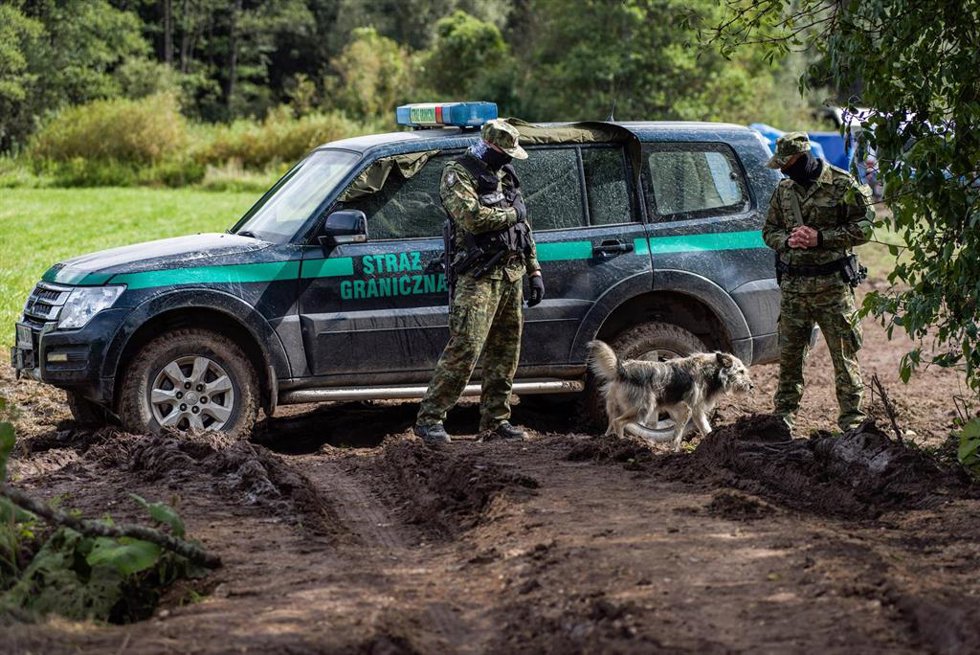 Agentes de policía montan guardia junto a la localidad de Usnarz Gorny, cerca de un campamento improvisado en el que se aloja un grupo de migrantes a los que no se deja pasar al lado polaco