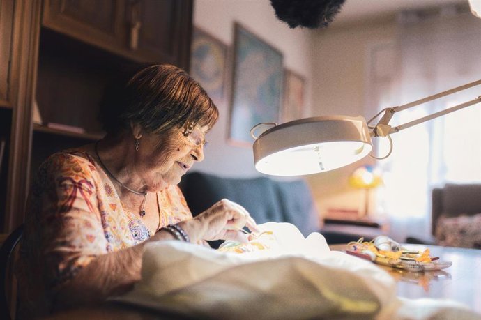 Una señora cosiendo en su casa.