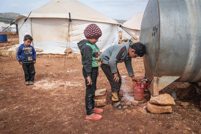 Archivo - Niños sacan agua en el campamento de refugiados sirios de Kafr Aruq