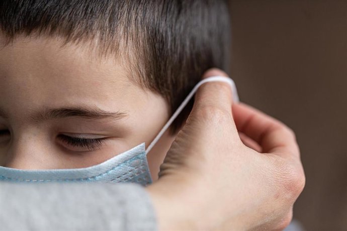 Archivo - Una madre coloca a su hijo una mascarilla 