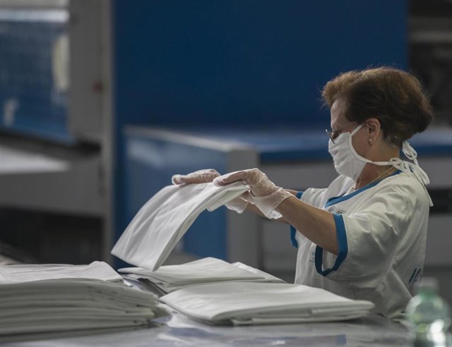 Archivo - Una trabajadora durante el proceso de empaquetado en Ilunion Lavanderia, en foto de archivo.