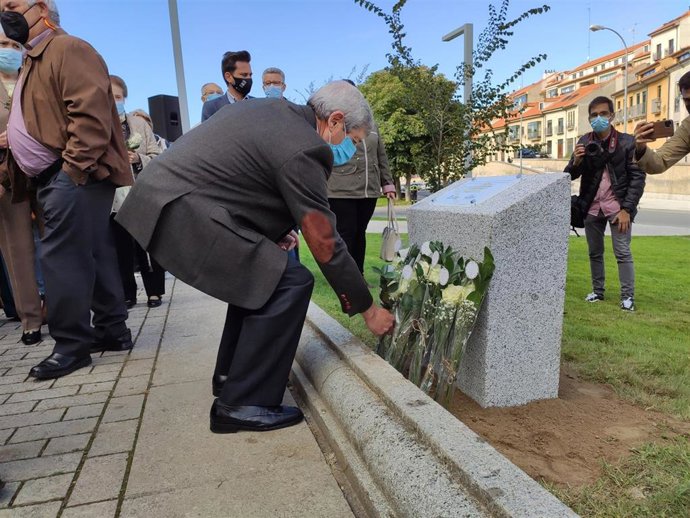 Asistente coloca una flor delante del monolito en recuerdo de las personas mayores que han fallecido y han sufrido las consecuencias de la pandemia del coronavirus.