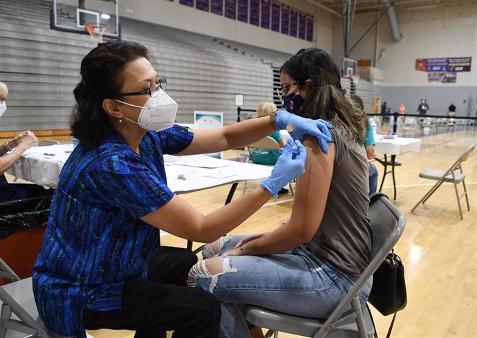 11 September 2021, US, Winter Springs: Nurse Susanna Bryan (L)administers a dose of the Pfizer COVID-19 vaccine to Joann Cortes at a vaccination clinic at Winter Springs High School.