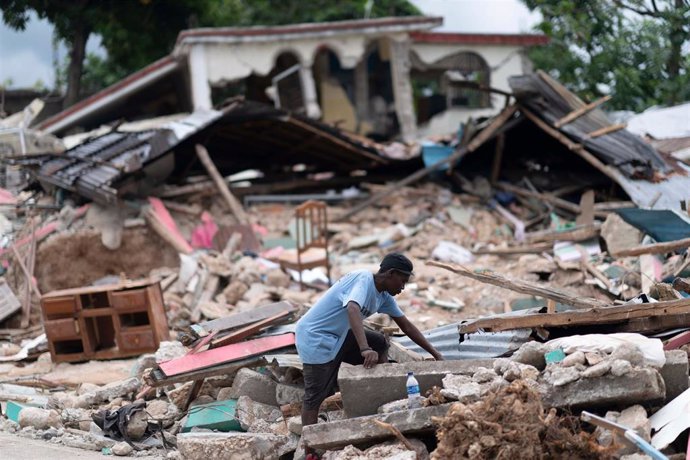 Archivo - Un hombre busca entre los escombros tras el terremoto en Les Cayes, Haití
