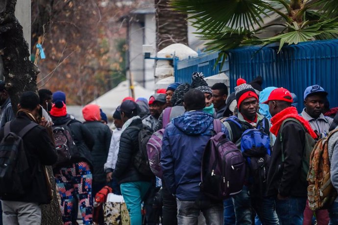 Archivo - Migrantes de Haití esperan frente a la embajada de su país en Santiago para resolver su situación migratoria. 