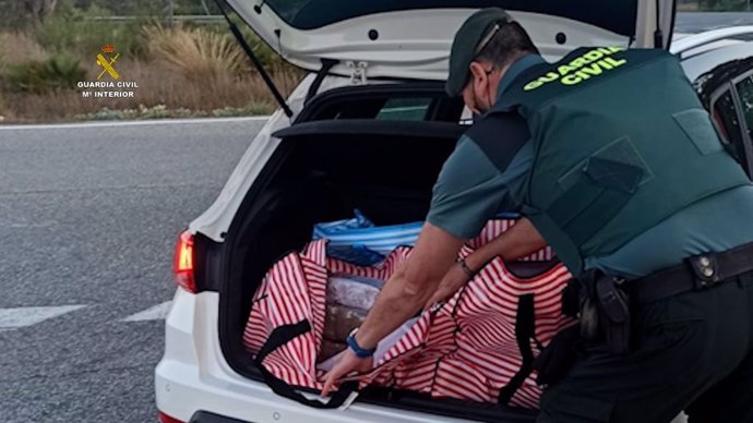 Un agente de la Guardia Civil intercepta droga en el maletero de un coche.