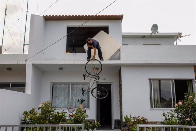 Un hombre del núcleo urbano de Todoque saca su bicicleta por la ventana durante el desalojo de sus viviendas ante la aproximación de la lava del volcán