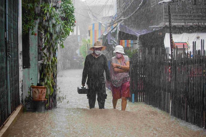 03 October 2021, Thailand, Nonthaburi: People walk through a submerged alley during a heavy monsoon rains in Thailand. Photo: Varuth Pongsapipatt/SOPA Images via ZUMA Press Wire/dpa