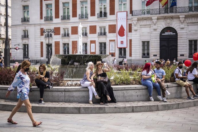 Archivo - Varias personas sin mascarilla en la fuente de la Puerta del Sol.