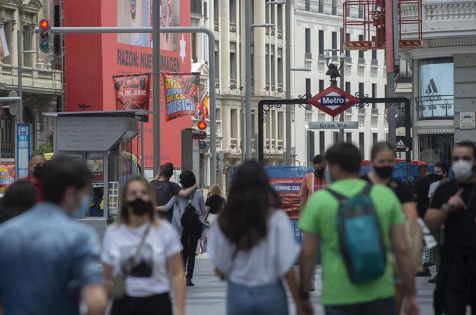 Archivo - Varias personas caminan por la Gran Vía con mascarilla.