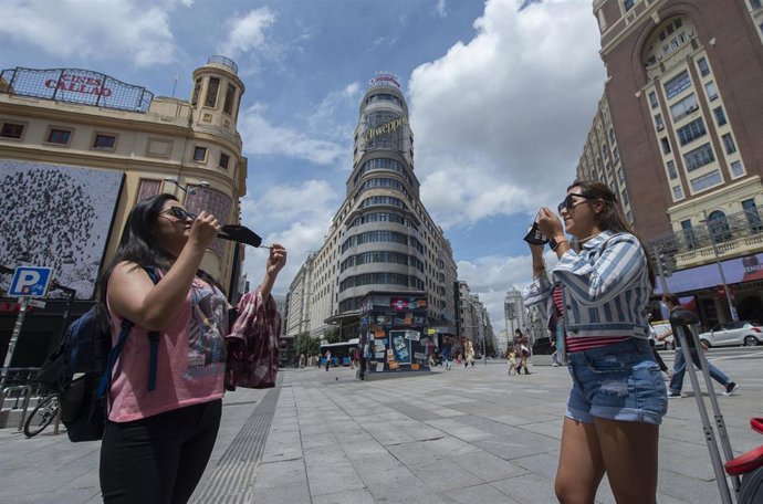 Archivo - Dos mujeres se ponen la mascarillas, después de quitársela para una foto, en la Gran Vía