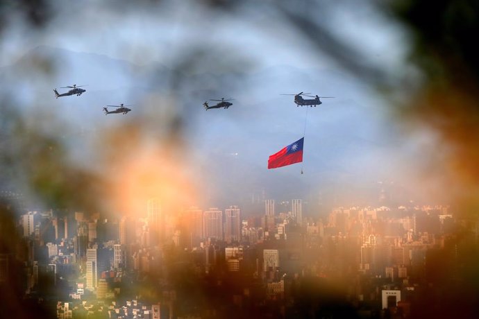 05 October 2021, Taiwan, New Taipei City: A military helicopter carrying a tremendous Taiwan flag conducts a flyby rehearsal with other helicopters ahead of the Double-tenth National Day celebration, near Taipei 101, amid China's growing military threat