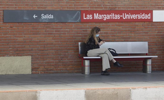 Archivo - Una joven espera sentada en el andén de la Renfe Las Margaritas-Universidad