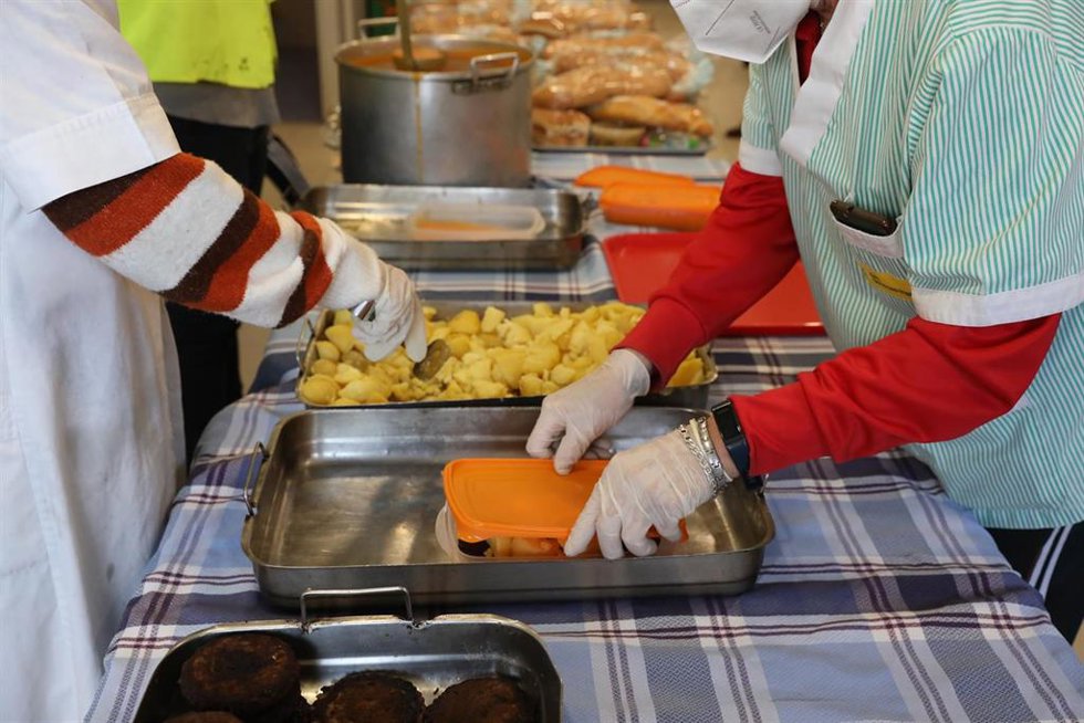 Archivo - Una cocinera (i) sirve comida varias raciones de comida a voluntarios (d) del Comedor Social San José