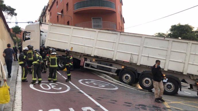 Bombers de Barcelona i la grua de Transports Metropolitans de Barcelona treballen per retirar el camió articulat