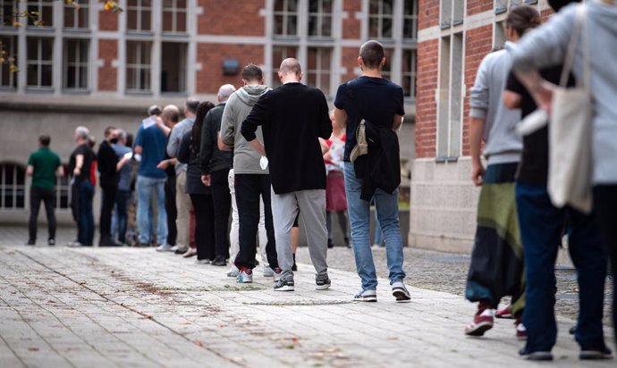 26 September 2021, Berlin: People queue in long lines in front of the polling stations at the Jane Addams School, as they wait to cast their votes for the Berlin House of Representatives elections. Photo: Bernd von Jutrczenka/dpa