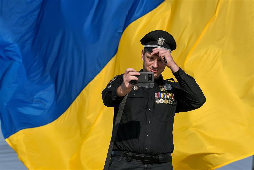 Archivo - Un policía se hace una foto frente a la bandera de Ucrania