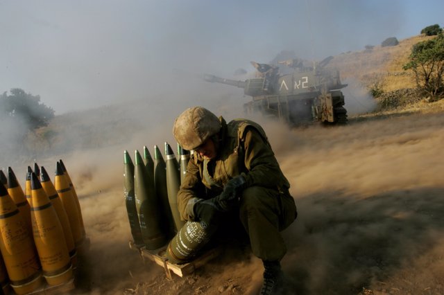 Un soldado israelí se aferra a un proyectil de artillería de 155 mm mientras un cañón móvil abre fuego durante un bombardeo contra objetivos de Hezbolá en el sur del Líbano 