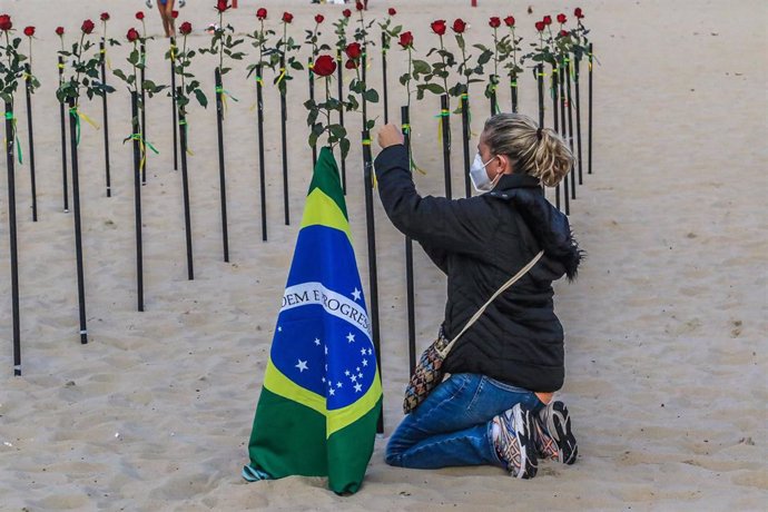 Archivo - Una mujer coloca una rosa durante una protesta de activistas de la ONG Río de Paz en la playa de Copacabana por la gestión de la pandemia en el país.