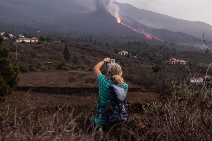 Un hombre toma una foto del volcán de Cumbre Vieja en La Palma cuando vuelve a expulsar lava y piroclastos tras horas de relativa inactividad, a 27 de septiembre en Tacande de Abajo, El Paso, La Palma, Santa Cruz de Tenerife, Canarias (España).