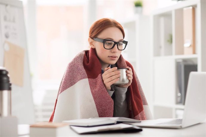 Archivo - Mujer con frío en la oficina.