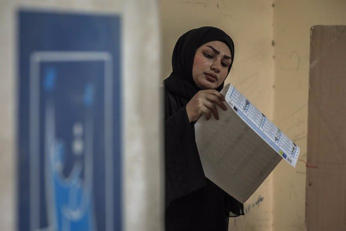 10 October 2021, Iraq, Baghdad: An Iraqi woman checks the list of candidates at a polling station in the Habibiya neighbourhood, before casting her vote during the Iraqi parliamentary elections. Photo: Ameer Al Mohammedaw/dpa
