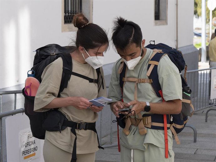Dos peregrinos consultan un teléfono móvil en las inmediaciones de la Oficina del Peregrino, a 9 de octubre de 2021, en Santiago de Compostela, A Coruña, Galicia (España). Galicia amplía desde este sábado el aforo en interiores, así como las reuniones e