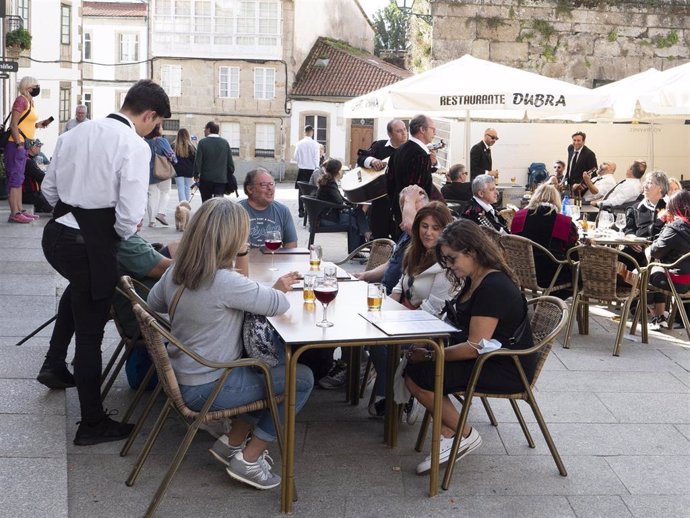 Un grupo de turistas consulta una carta en la terraza de un bar en Santiago de Compostela.