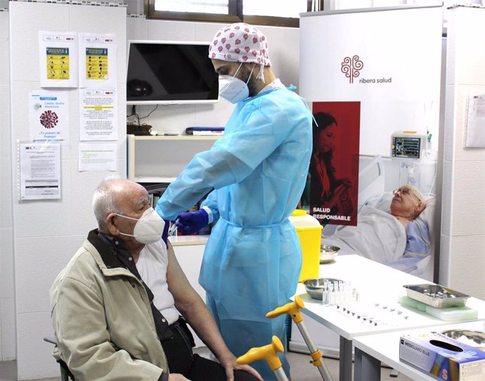 Archivo - Un profesional de Ribera vacuna a un anciano