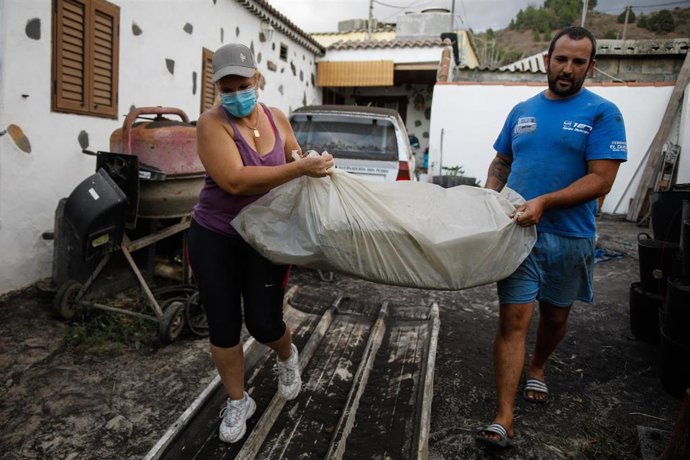Un hombre y una mujer sacan sus pertenencias de su casa por la actividad del volcán de Cumbre Vieja