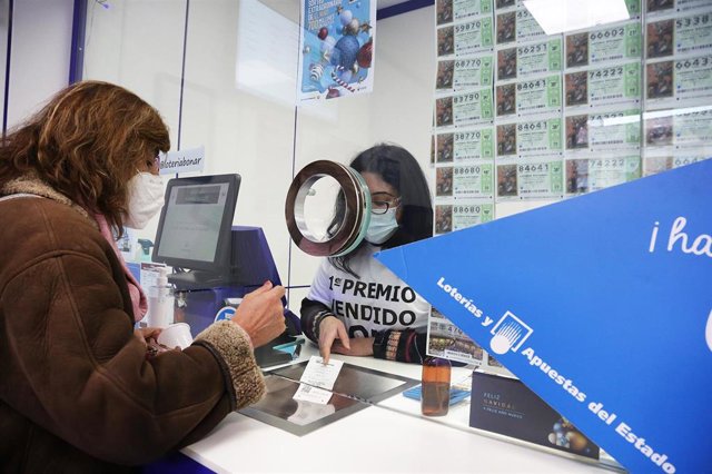 Un acertante en Benidorm (Alicante) gana más de 1,6 millones de euros en el sorteo de 'La Bonoloto' Archivo - Una lotera atiende a una clienta en la administración de lotería