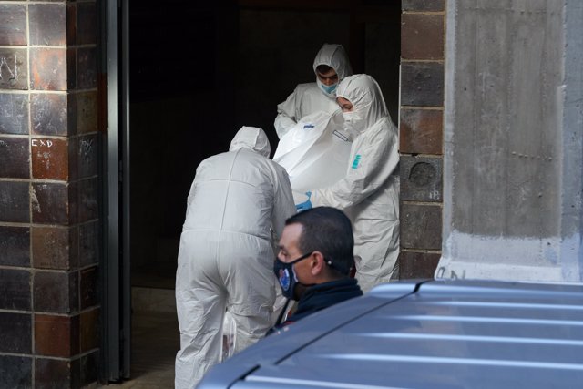 Agentes de la Ertzaintza junto a un vehículo de una funeraria en las inmediaciones de una vivienda del barrio Sansomendi de la capital alavesa donde un varón ha asesinado presuntamente a su esposa, a 12 de octubre de 2021, en Vitoria, Álava, Euskadi 