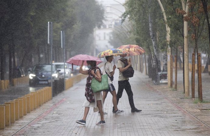 Varias personas caminan bajo sus paraguas durante una tormenta en Sevilla el día 14 de septiembre de 2021