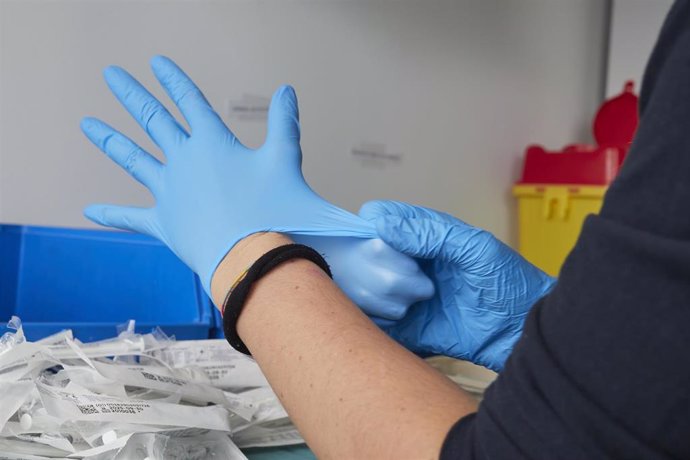 Archivo - Una profesional sanitaria se pone guantes de nitrilo en un dispositivo de vacunación contra el Covid-19 .