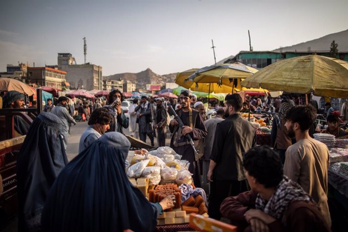 23 September 2021, Afghanistan, Kabul: A Taliban fighter stands amidst shoppers at a market in Kabul. Photo: Oliver Weiken/dpa