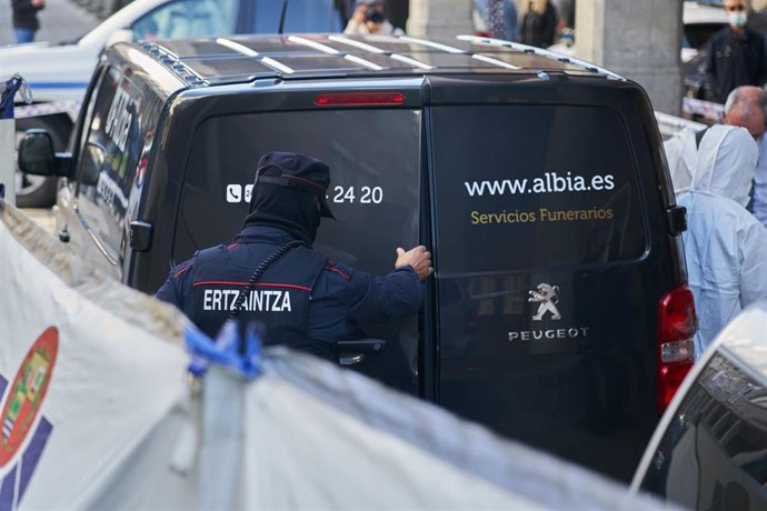 Un vehículo de una funeraria y un agente de la Ertzaintza en las inmediaciones de una vivienda del barrio Sansomendi de la capital alavesa donde un varón ha asesinado presuntamente a su esposa, a 12 de octubre de 2021, en Vitoria