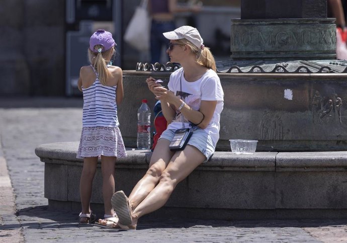 Archivo - Una mujer con una niña sentadas en el centro de la capital.