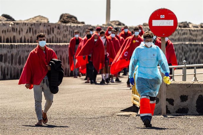 Archivo - Un trabajador de la Cruz Roja con varios migrantes rescatados por Salvamento Marítimo