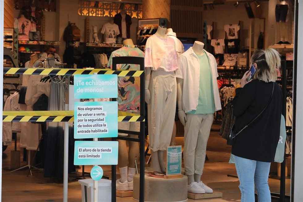 Archivo - Una mujer habla por teléfono en la entrada a una tienda de ropa del Centro Plaza Norte 2, La Cúpula de Madrid