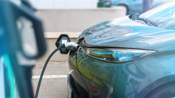 Archivo - Plugged in charger into an electric car at charge station