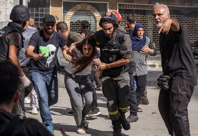 14 October 2021, Lebanon, Beirut: Civilians run for cover after gunfire erupted at a protest by supporters of the Shiite Hezbollah movement against the judge investigating the city's port port blast, near the former civil war front-line between Muslim S